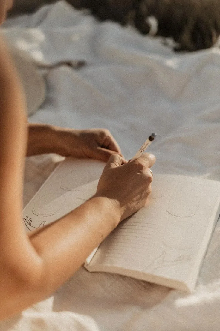 Mano escribiendo en un diario a la luz cálida, en un momento de reflexión